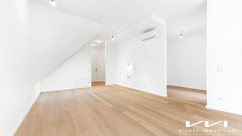Heller, leerer Raum mit Holzboden und Dachschräge, bereit für die individuelle Gestaltung.