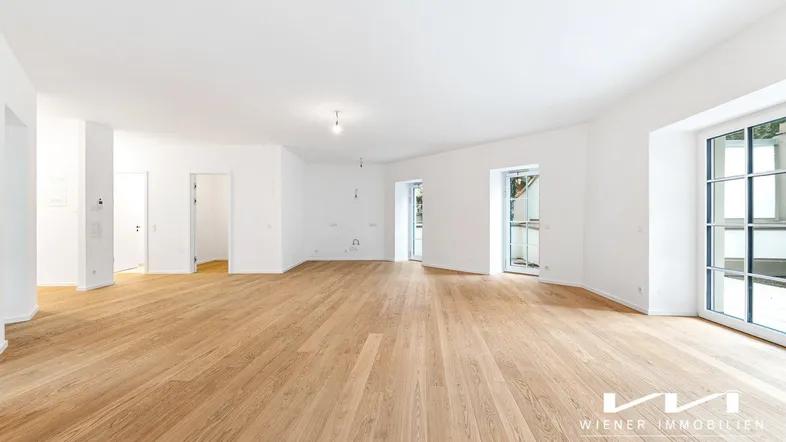 Heller und geräumiger Wohnbereich mit hochwertigem Parkettboden und Zugang zu Außenbereichen.