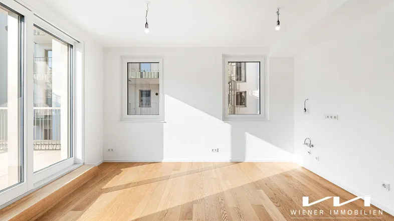 Heller, unmöblierter Raum mit Eichenparkett und Zugang zu einem großen Balkon.