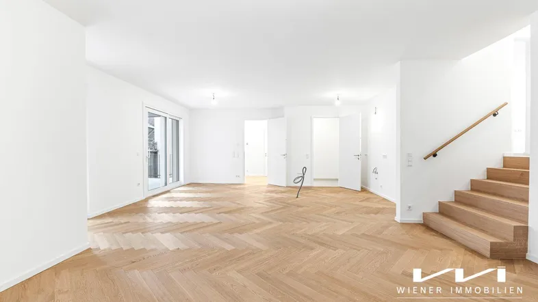 Geräumiges, helles Zimmer mit Fischgrätparkett und Zugang zu einem Balkon oder einer Terrasse.