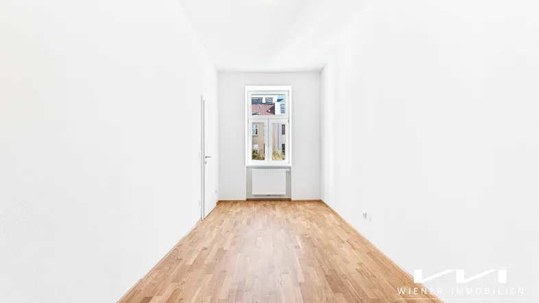 Heller, leerer Raum mit Parkettboden und einem Fenster, bereit zur individuellen Gestaltung.