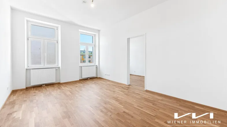 Helles Zimmer mit frisch gestrichenen weißen Wänden und neu verlegtem Parkettboden, bereit zum Einzug.