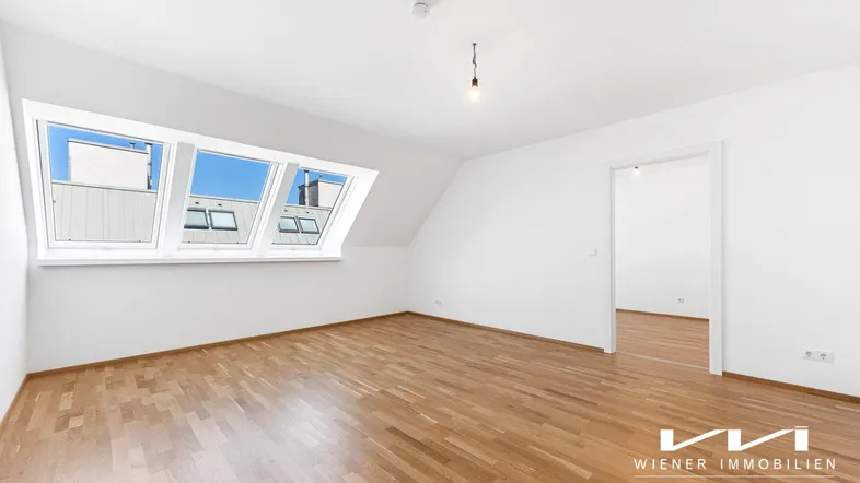 Helles Zimmer im Dachgeschoss mit Holzboden und schrägen Fenstern, ideal als Schlaf- oder Wohnbereich.