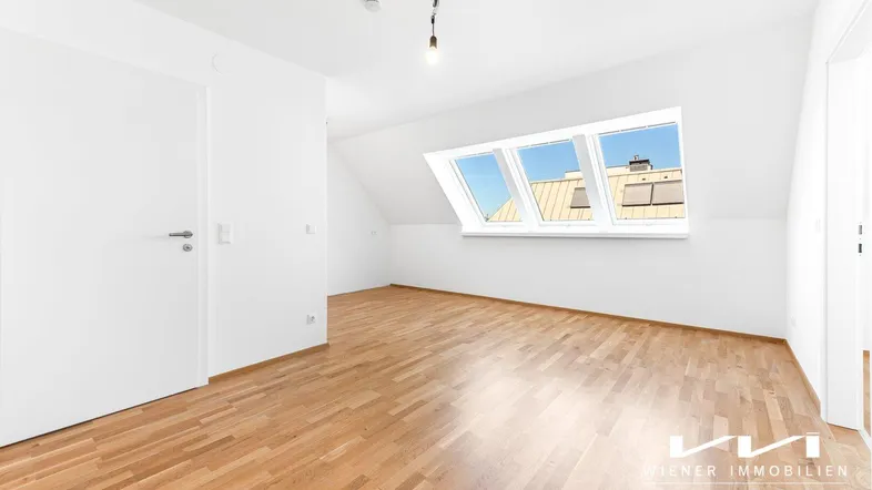 Helles Zimmer im Dachgeschoss mit Holzboden und großen Dachfenstern, bereit zur Einrichtung.
