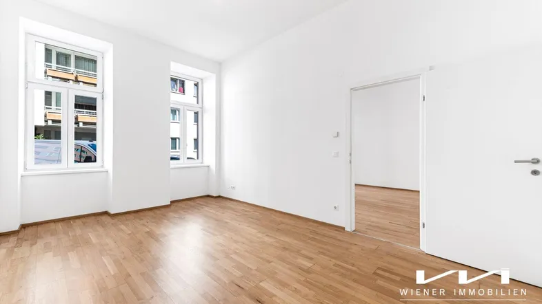 Heller, leerer Raum mit Parkettboden und hohen Fenstern, bereit zur individuellen Gestaltung.