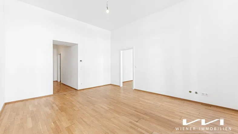 Heller, leerer Raum mit weiß gestrichenen Wänden und hellem Parkettboden, bereit zur individuellen Gestaltung.