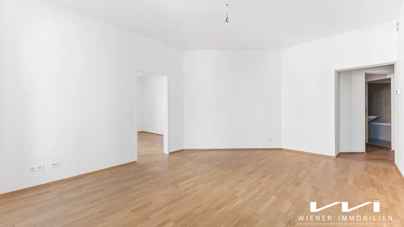 Helles, leeres Zimmer mit Parkettboden und weißen Wänden, bereit zur individuellen Gestaltung.
