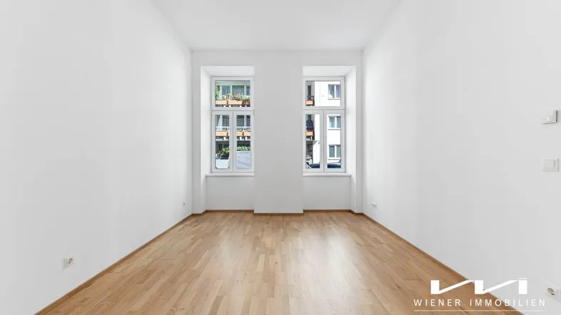 Helles Zimmer mit weißen Wänden und Holzboden, ideal für Wohn- oder Schlafbereich.
