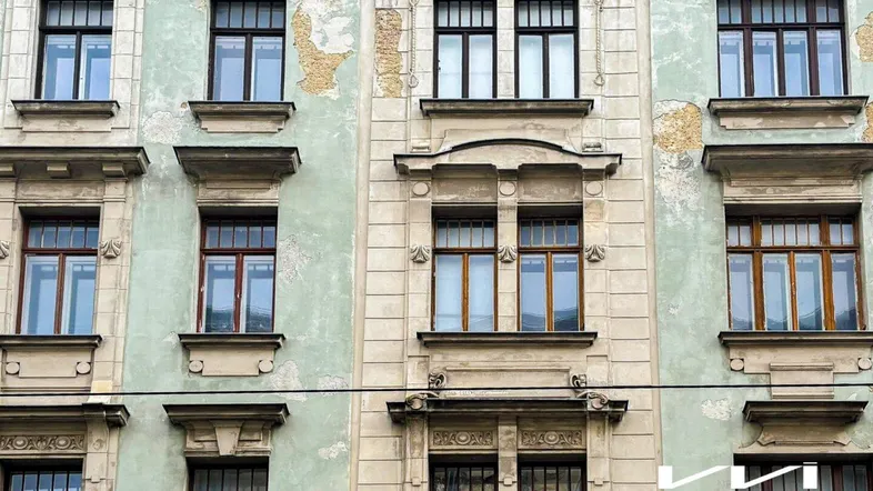 Fassade eines Altbaus mit abblätterndem Putz und vielen Fenstern, die den Charme des Gebäudes unterstreichen.