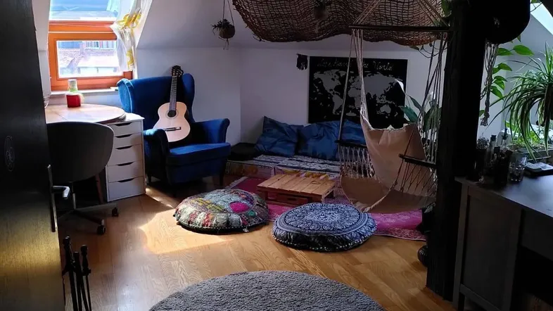 Kreativ eingerichteter Dachbodenraum mit blauer Sitzecke, Gitarre und einem großen Dachfenster für Tageslicht.