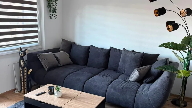 Gemütliches Wohnzimmer mit großem Ecksofa, modernem Couchtisch und Holzboden.