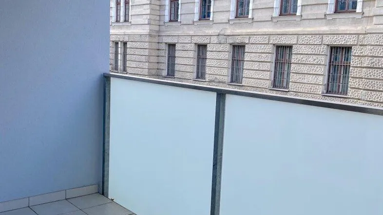 Balkon mit Fliesenboden und Blick auf die gegenüberliegende historische Fassade eines Gebäudes.
