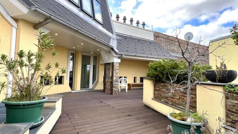 Geräumige Dachterrasse mit Holzboden und Pflanzen, ideal für Entspannung im Freien.