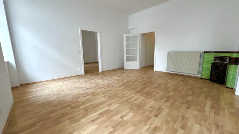Helles, leeres Zimmer mit Parkettboden und zwei Türen, bereit zur individuellen Gestaltung.