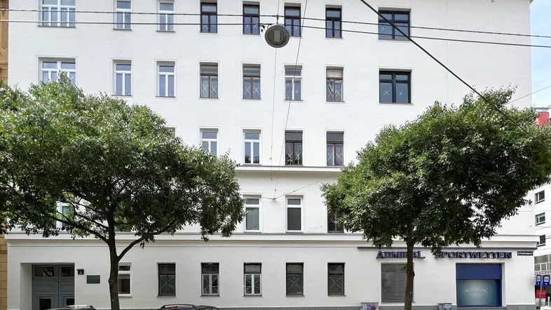 Ansicht der modernen Gebäudefassade mit vielen Fenstern und parkenden Autos auf der Straße.