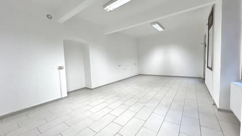 Heller, leerer Geschäftsraum mit weißen Wänden und modernen Fliesenboden, ideal für verschiedene Nutzungen.