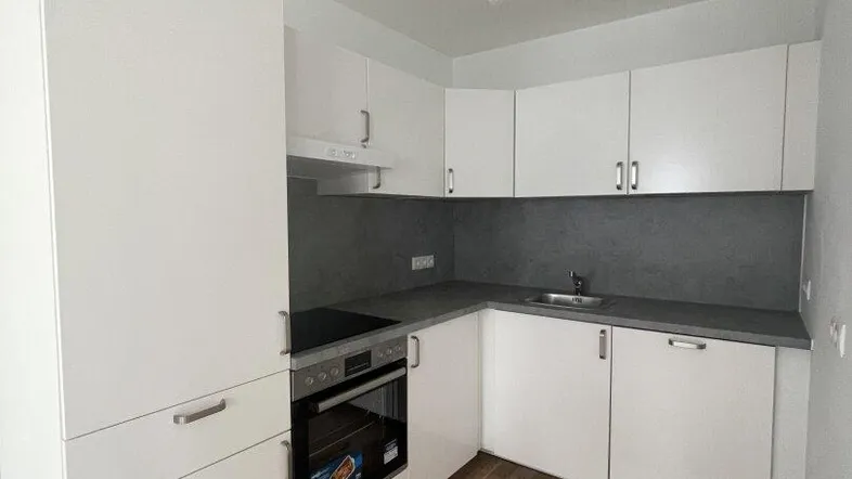 Moderne Einbauküche mit weißen Schränken, grauer Arbeitsplatte und integrierten Geräten.