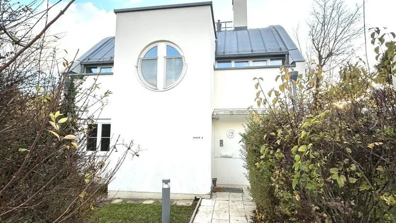Modernes weißes Haus mit einzigartigem runden Fenster und gepflastertem Zugangsweg.