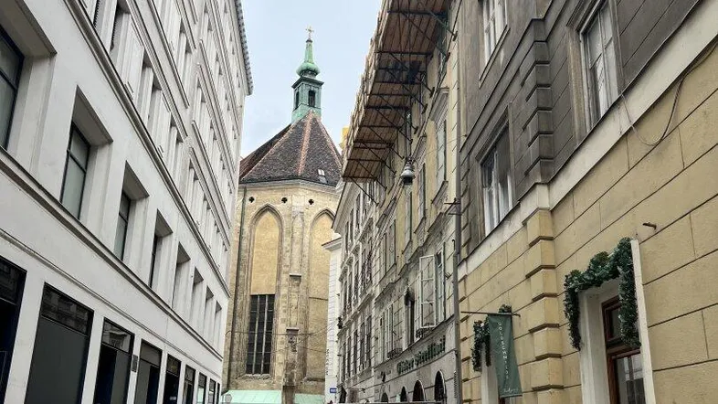 Historische Gasse in der Stadt mit Kopfsteinpflaster und einer Kirche im Hintergrund.