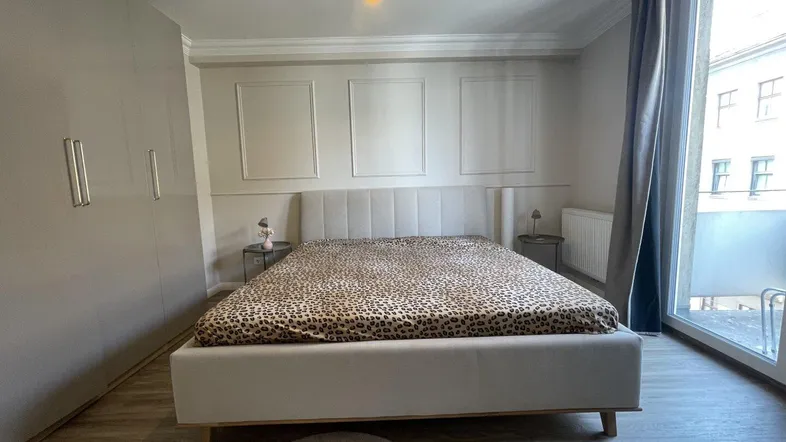 Helles Schlafzimmer mit großem Bett, Einbauschrank und Zugang zu einem Balkon.