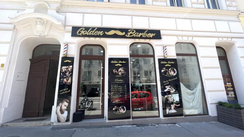 Historisches Gebäude mit einer gut erhaltenen Fassade und einem Friseursalon im Erdgeschoss mit großen Schaufenstern.