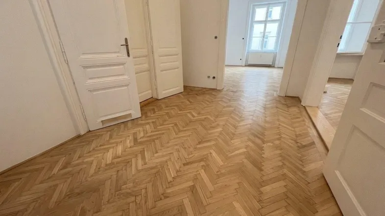 Helles Entree mit Fischgrätparkettboden und Zugang zu mehreren Zimmern in einem Altbau.
