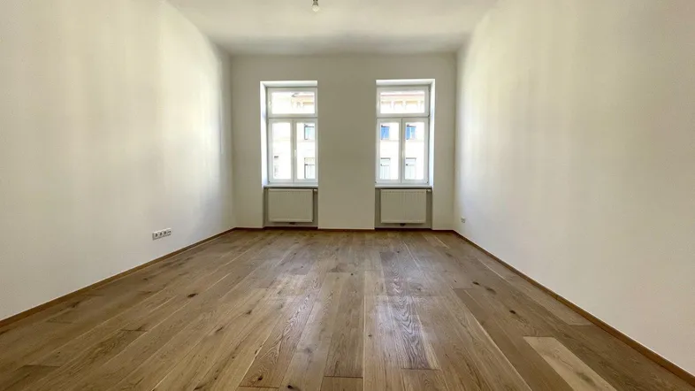 Helles Zimmer mit neuem Holzplankenboden und zwei Fenstern, bereit zur individuellen Gestaltung.
