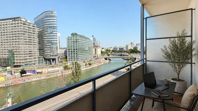 Balkon mit Holzboden und Glasabtrennung bietet einen weiten Blick auf die Stadt und den Fluss.