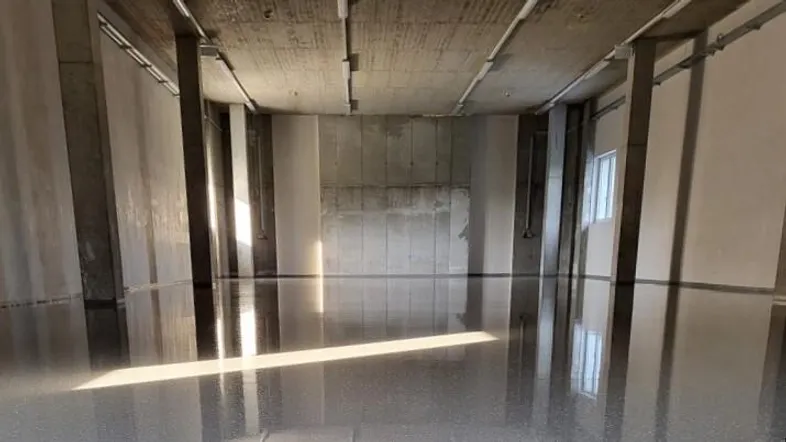 Großer, leerer Raum mit poliertem Betonboden, sichtbaren Säulen und Decken, ideal für industrielle Nutzung.