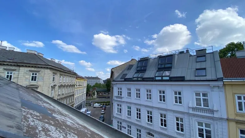 Panoramablick über die Dächer einer städtischen Umgebung mit einer belebten Straße und historischen Gebäuden.