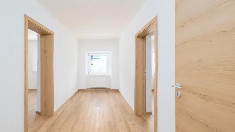 Heller Flur mit Holzboden und mehreren Türen, der zu verschiedenen Räumen führt.