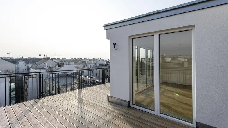 Große Dachterrasse mit Holzboden und weitem Blick über die Stadt bei Sonnenuntergang.