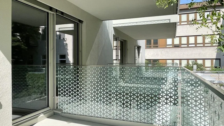 Moderner Balkon mit Glasgeländer und Blick auf die umliegenden Gebäude.