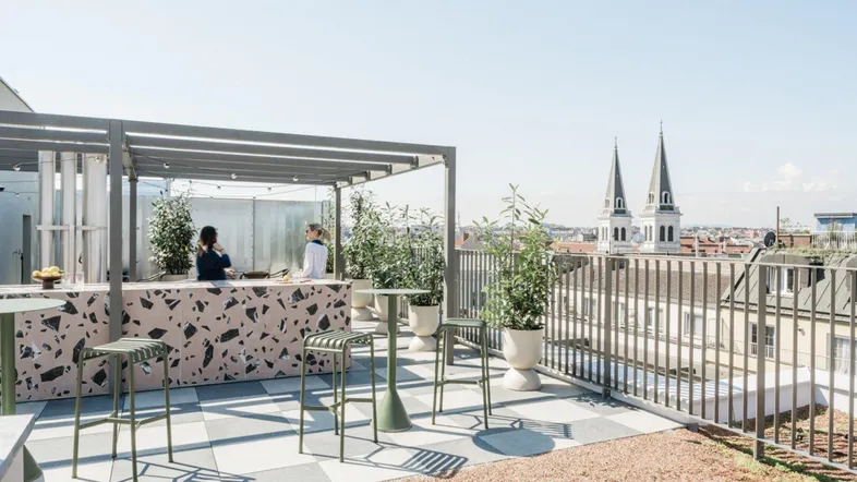 Moderne Dachterrasse mit Bar, Sitzgelegenheiten und weitem Blick über die Stadt.