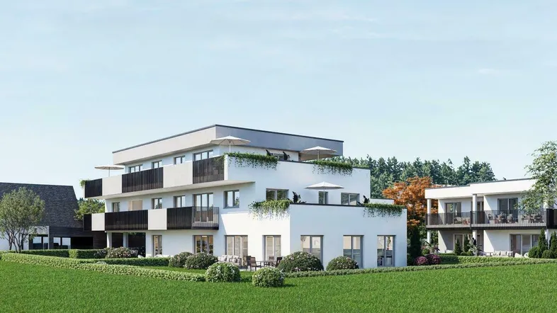 Moderne Wohnanlage mit weißer Fassade, Balkonen und Dachterrassen, umgeben von viel Grün.
