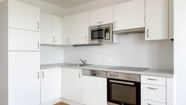 Moderne Einbauküche in Weiß mit integrierten Geräten und hellem Holzfußboden, ideal für den täglichen Gebrauch.
