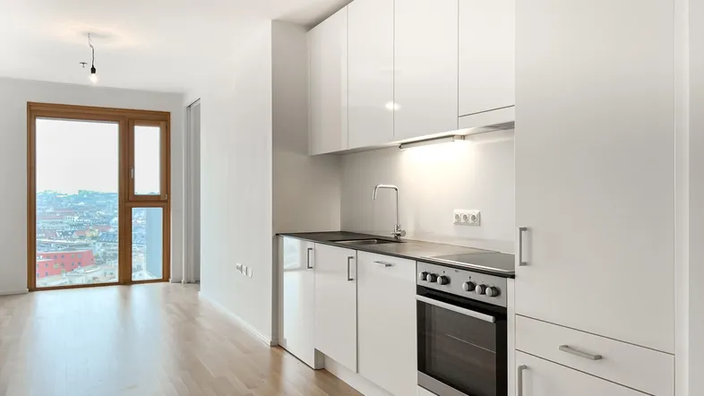 Moderne Einbauküche mit weißen Hochglanzfronten, Holzboden und großem Fenster mit Stadtblick.