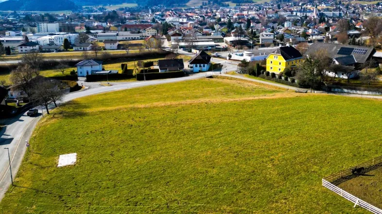 Luftaufnahme eines großen Grundstücks mit umliegenden Häusern und malerischer Bergkulisse.