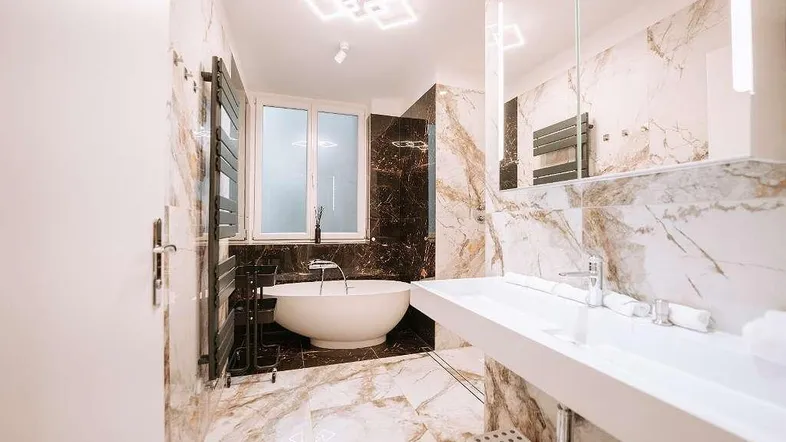 Modernes Badezimmer mit freistehender Badewanne, Doppelwaschbecken und luxuriösen Marmorfliesen.