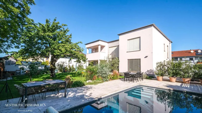 Moderner Gartenbereich mit Swimmingpool, Terrasse und Essbereich im Freien unter blauem Himmel.