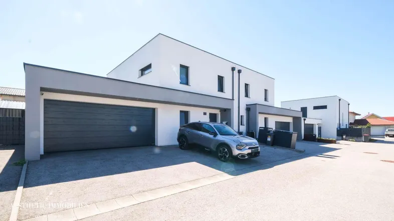Moderne Doppelhaushälfte mit integrierter Garage und Stellplatz im Freien.