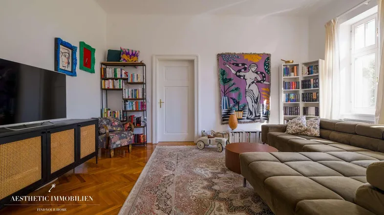 Helles Wohnzimmer mit Fischgrätparkett, bequemer Couch und farbenfroher Kunst an den Wänden.