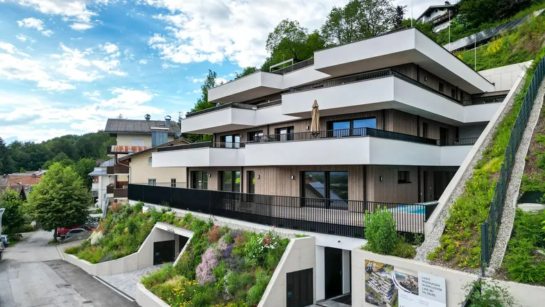 Modernes Mehrfamilienhaus in Hanglage mit Terrassen, Balkonen und integrierter Tiefgarage.