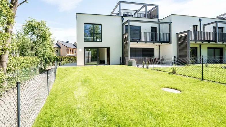 Modernes Reihenhaus mit privatem Garten und Balkon an einem sonnigen Tag.
