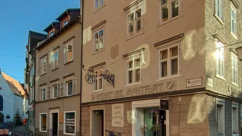 Historisches Gebäude an einer gepflasterten Straße mit traditioneller Architektur und Geschäften im Erdgeschoss.