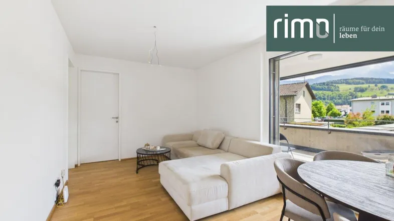 Helles Wohn- und Esszimmer mit Holzboden und Zugang zum Balkon, bietet einen weiten Blick.