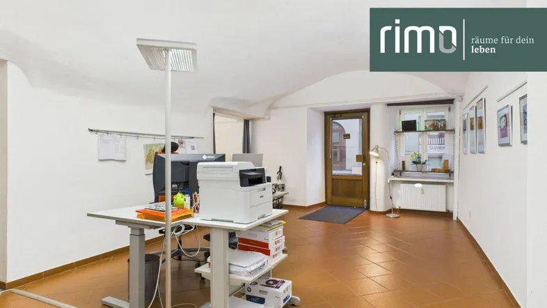 Geräumiges Büro mit gewölbter Decke, Terrakottafliesen und moderner Büroeinrichtung. Der Eingangsbereich ist sichtbar.