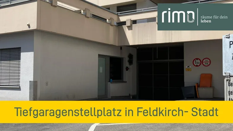 Eingangsbereich einer Tiefgarage mit Hinweisschildern und Gebäudefassade im Hintergrund.