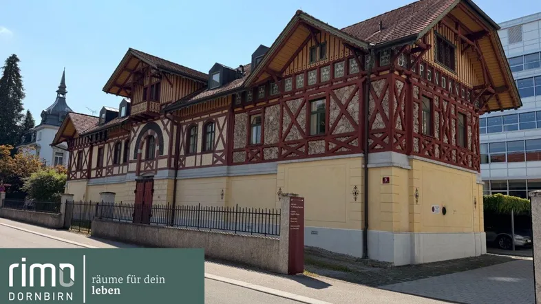 Historisches Gebäude mit traditioneller Holzfassade und gelben Wänden unter blauem Himmel.