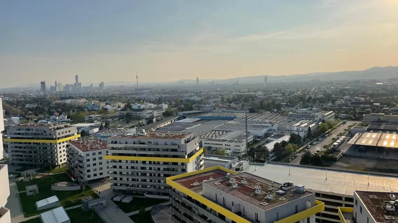 Weitläufige Stadtansicht mit Wohngebäuden und Industriegebiet unter einem klaren Himmel.